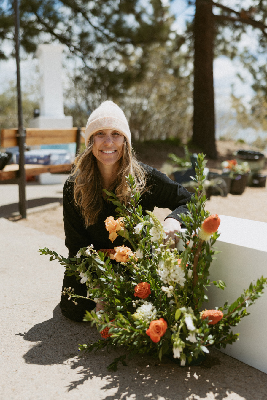 Brittany of Golden Flowers arranging a floral installation at an outdoor wedding